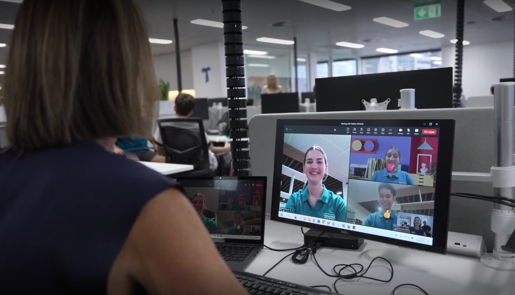 Teacher participating in a video lesson with students on a computer screen.