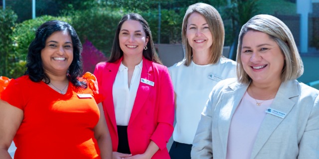 Four staff members standing outdoors and smiling at the camera.