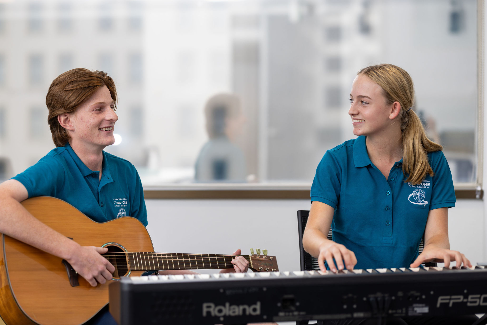 Two students playing guitar and keyboard together in a music room.
