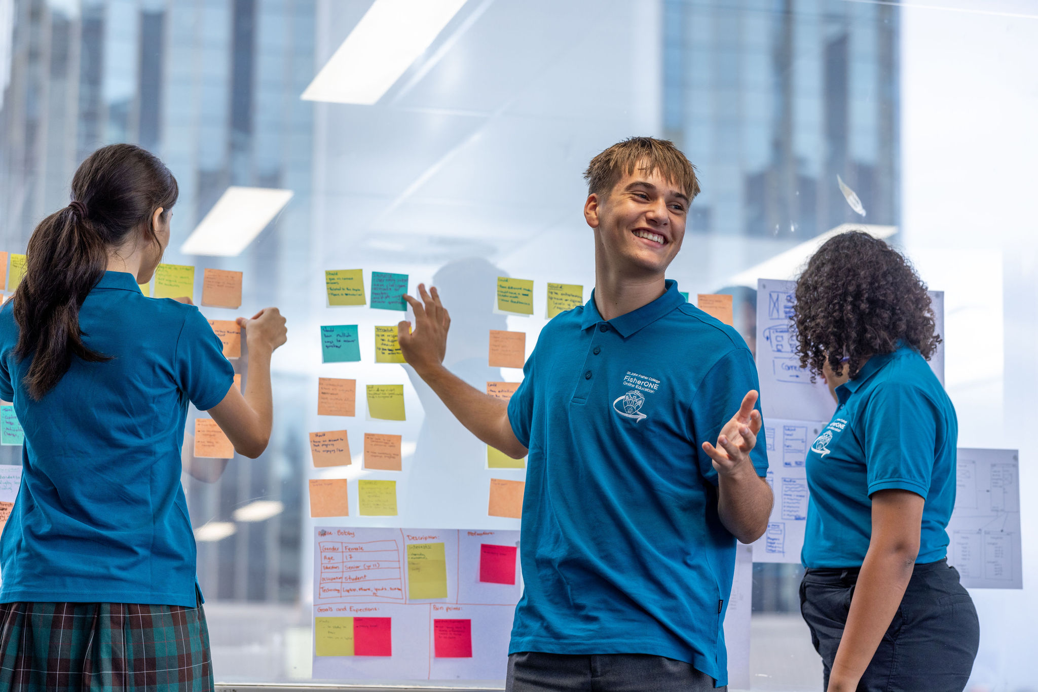 Students collaborating with sticky notes on a glass wall.