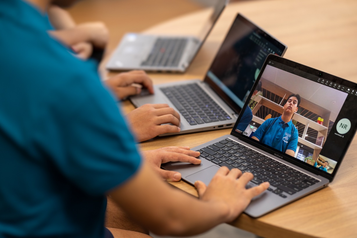 Students participating in an online lesson using laptops.