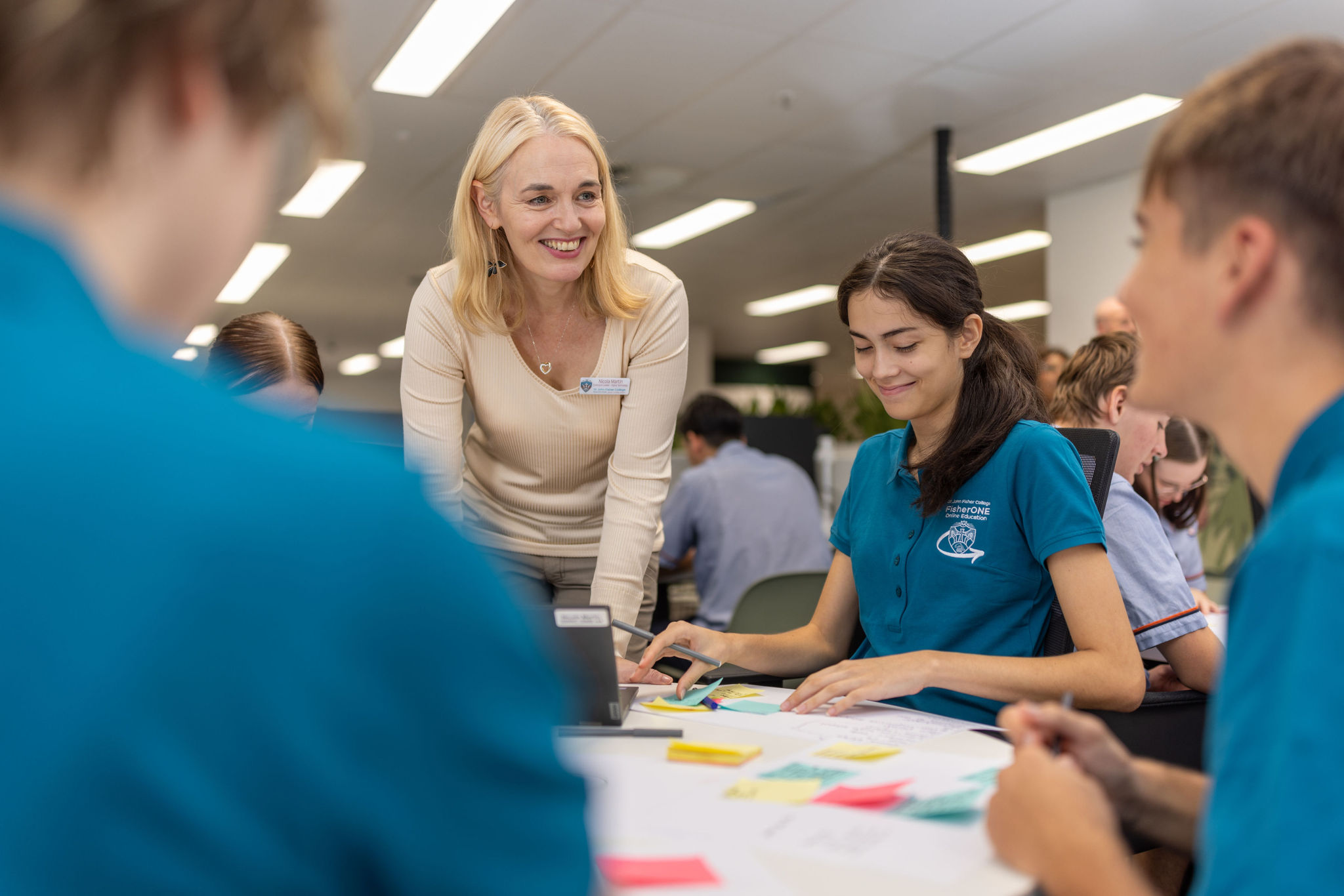 Teacher supporting students working together at a table.