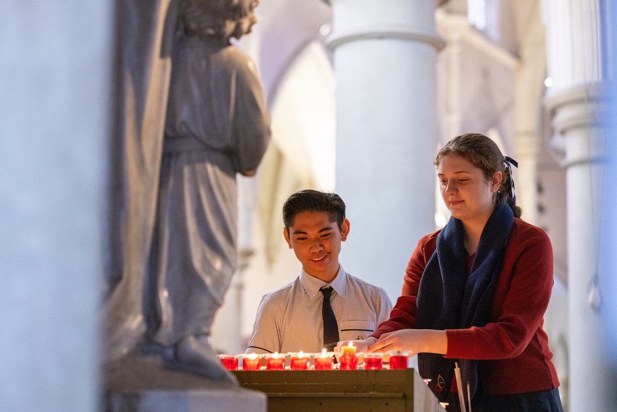 Students lighting candles inside a church.